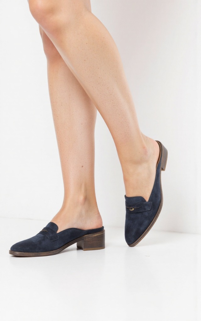 A female model wearing loafers, against a white background, with a close   up of the feet